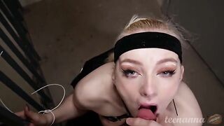 A young girl with blue eyes is deeply engaged in oral play outdoors