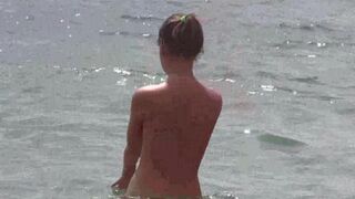 Nudists enjoy each other on the beach without clothes