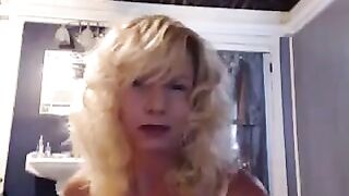 A golden-haired mature woman caresses herself in the bathroom with a toy