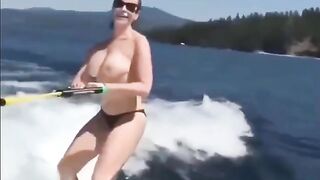 Topless girl water skiing, her tits splash water