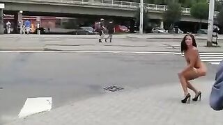 A sexy brunette with a beautiful body poses in public place