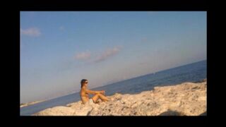 Nude sunbathing of a beautiful girl on the beach