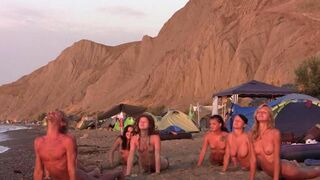 A group of naked people playing volleyball on the beach is really cool