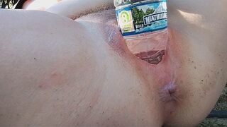A busty MILF pees in a bottle and masturbates outdoors